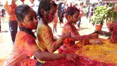 A vibrant Colour Fun Festival scene with kids painting, playing games, and engaging with native English speakers.