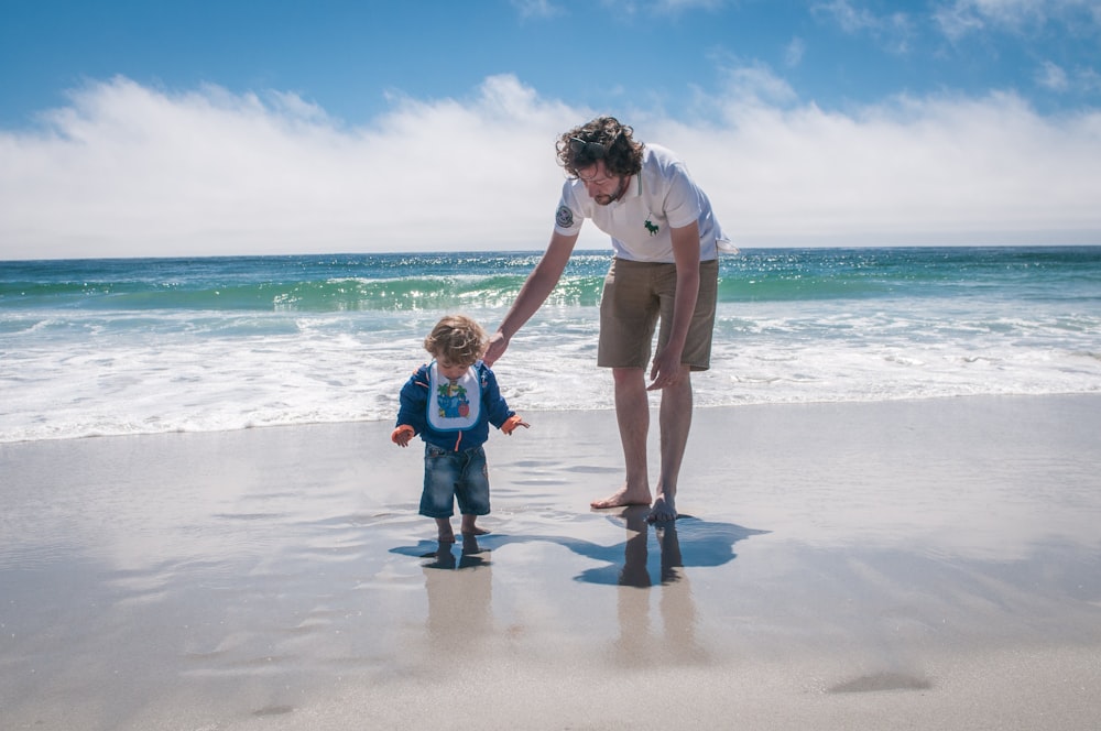 hombre y niño caminando al lado de la playa