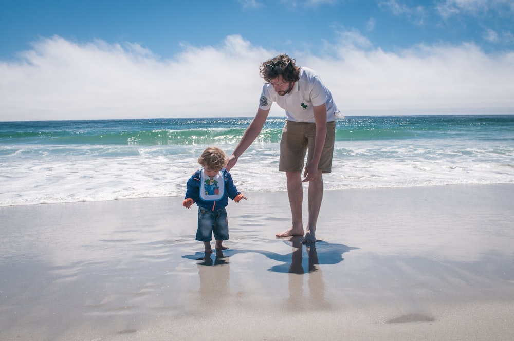 man and boy walking beside beach