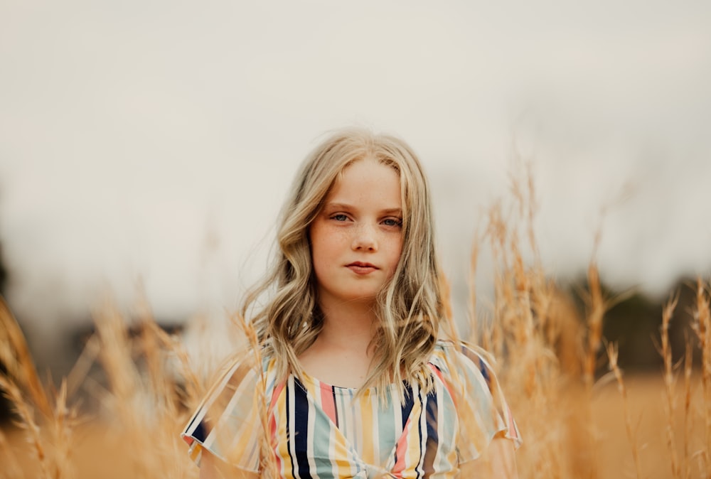 girl standing while smiling on grassfield during daytime