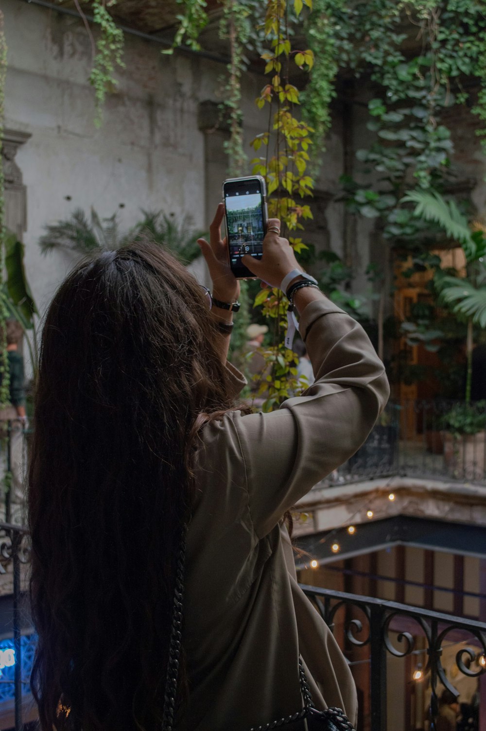 woman standing on balcony taking a photo using smartphone