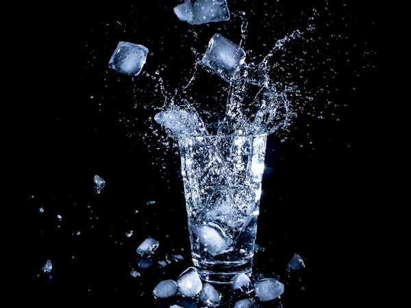 Ice splashing into a glass of water.