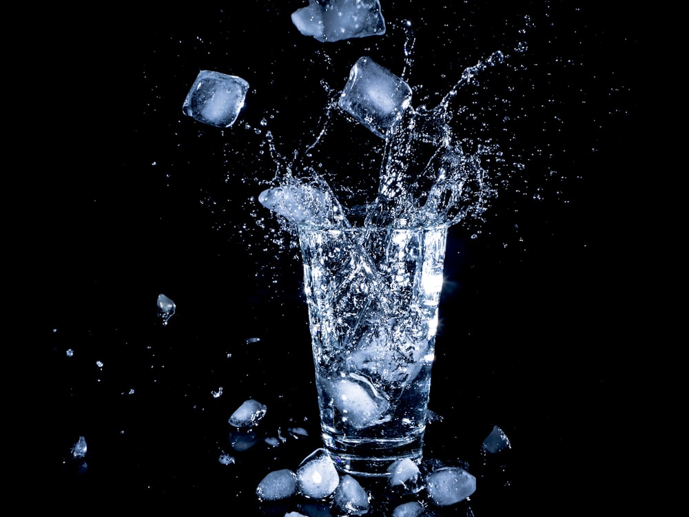 cubetti di ghiaccio caduti in una tazza trasparente con acqua