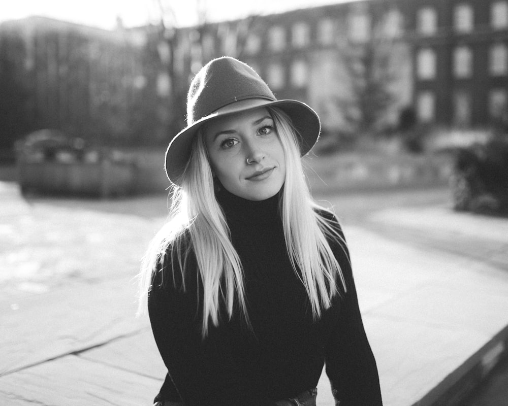 grayscale photography of woman sitting near building