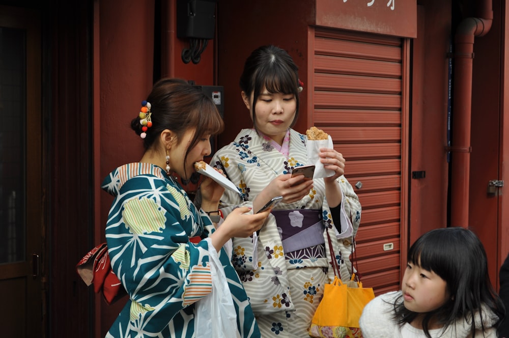 two women and one girl standing beside red wall