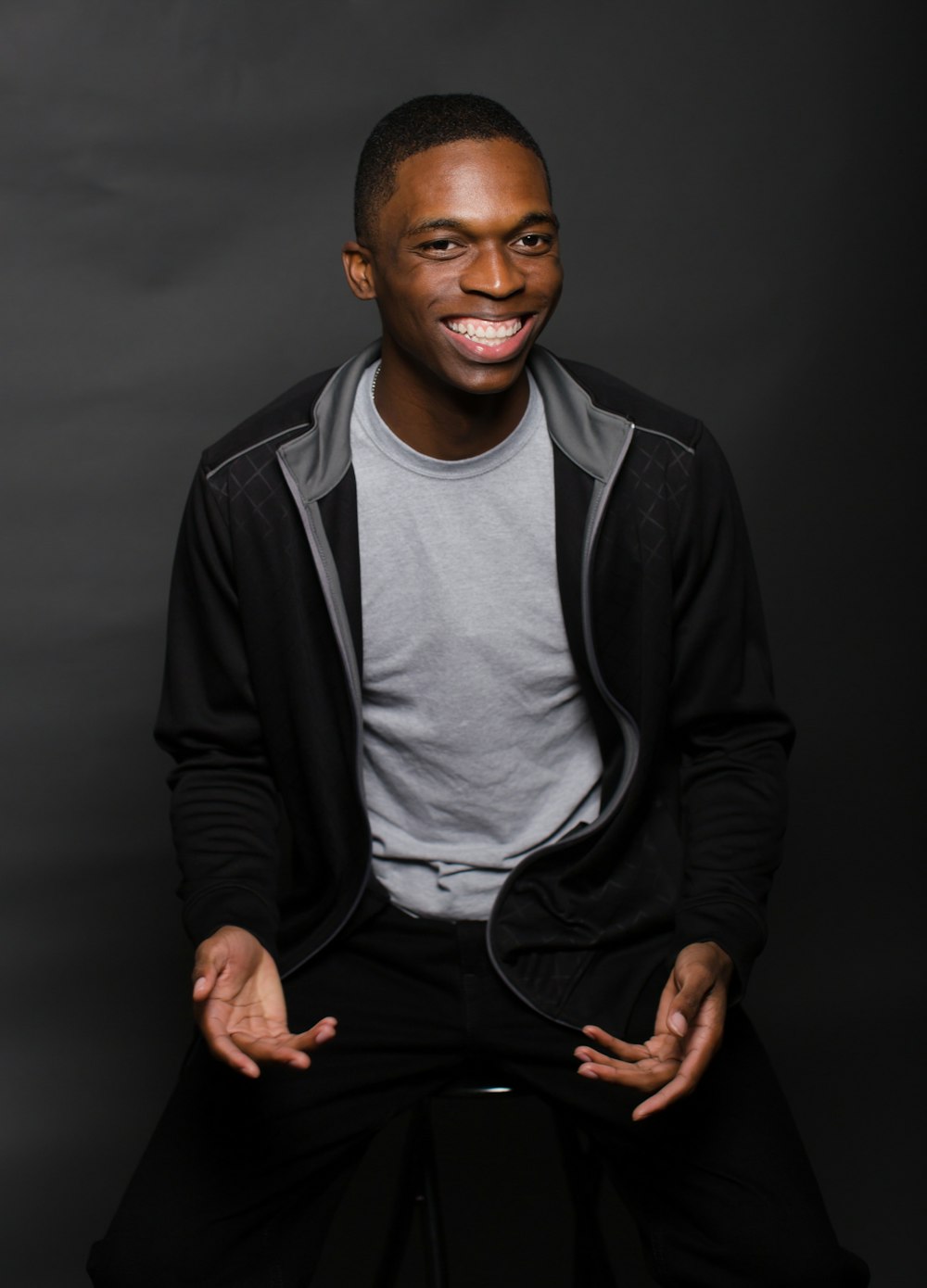 man wearing black zip-up jacket while sitting on chair