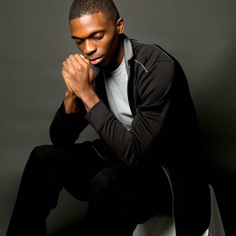 man sitting in black zip-up jacket