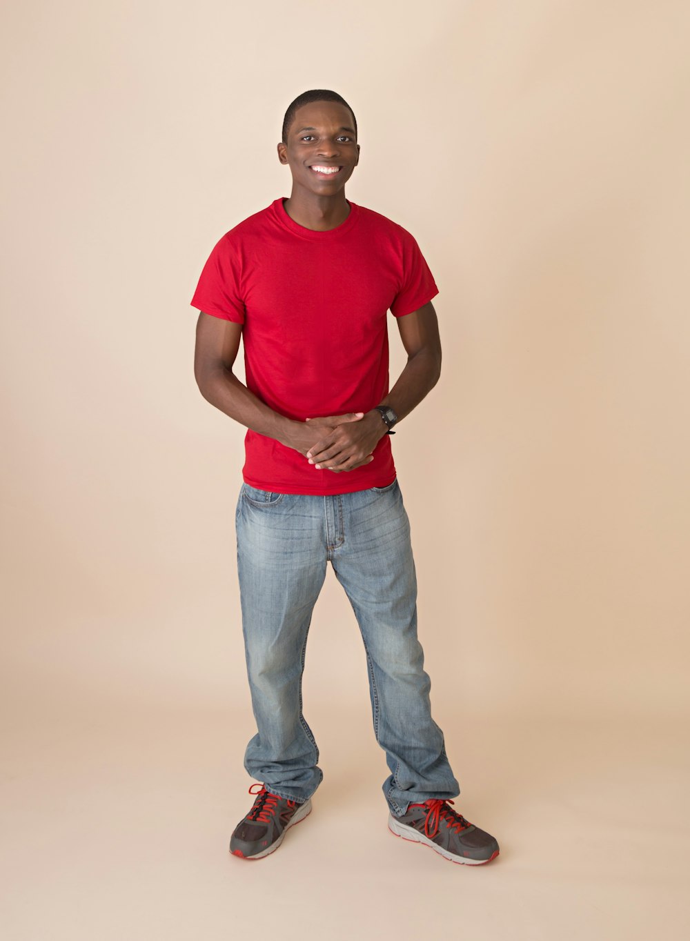 smiling man wearing red crew-neck t-shirt and gray denim jeans