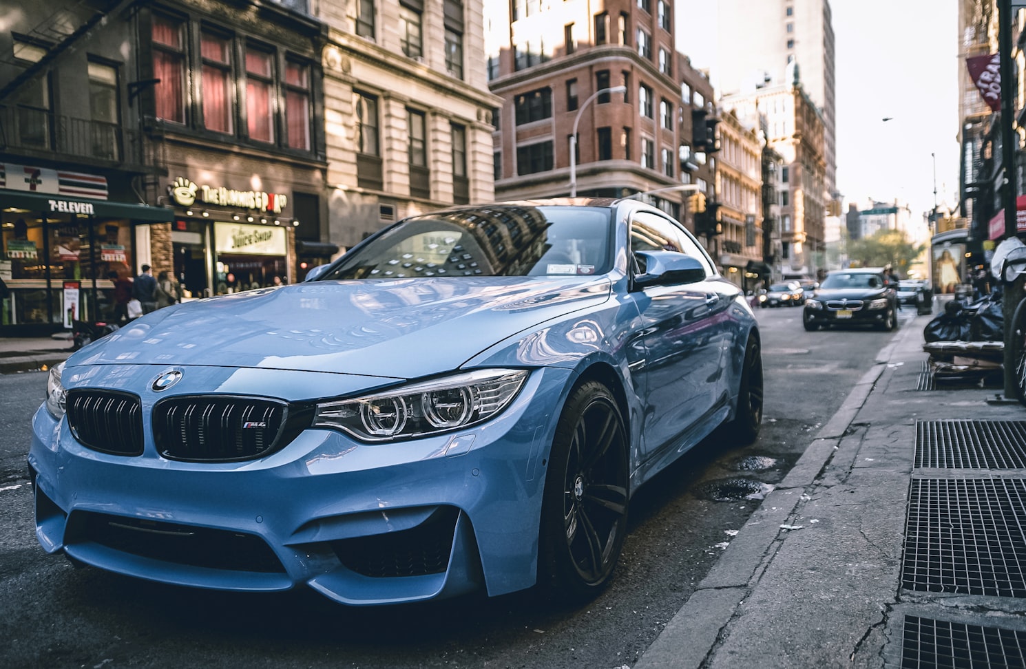 a closeup picture of a blue bmw parking on the street