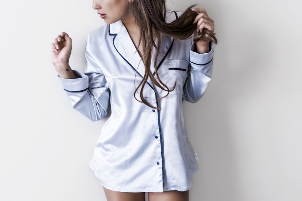 woman in white and black button-up coat leaning on wall