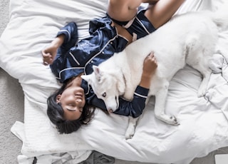 woman lying on bed with white Siberian husky