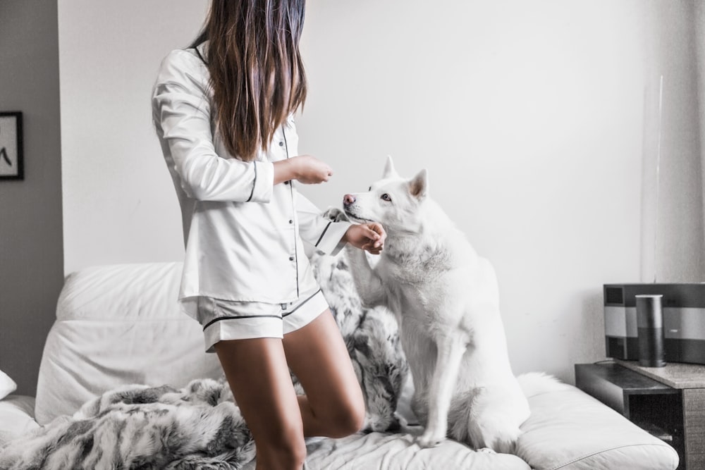 woman standing beside white dog sitting on sofa