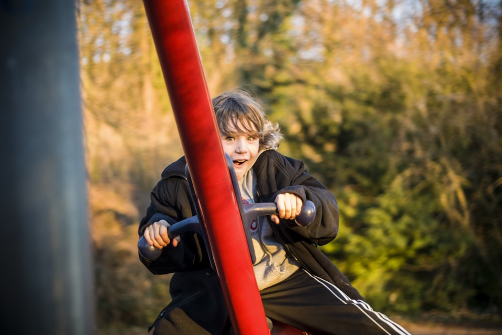 selective focus photography of boy riding on swing