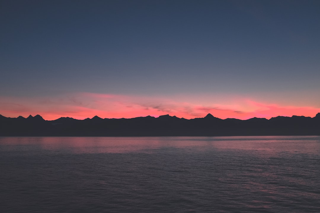 body of water near mountain during blue hour