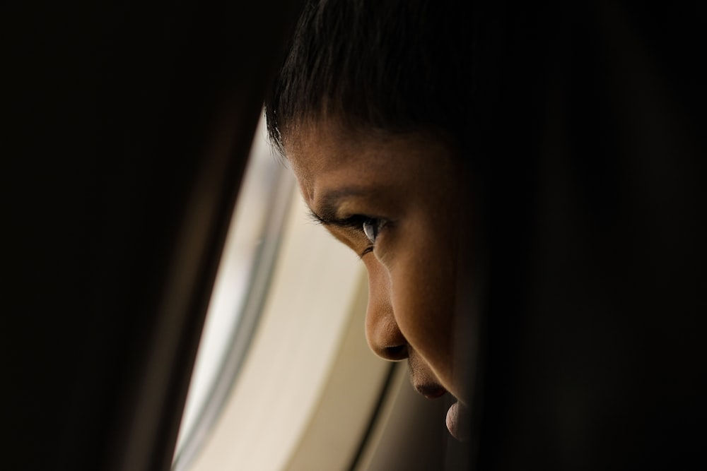 shallow focus photo of boy looking at window