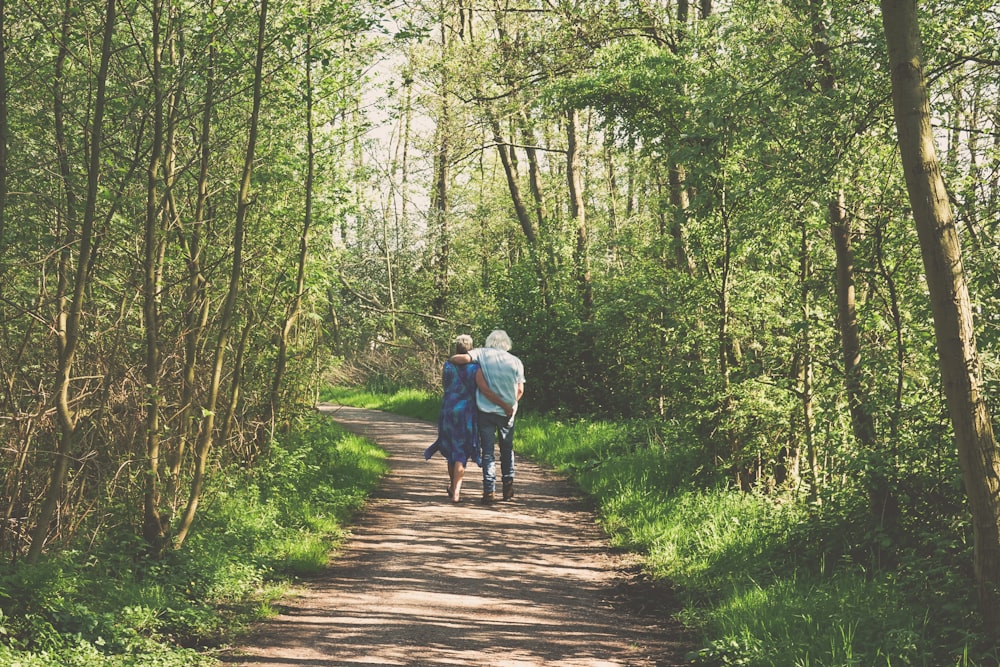 duas pessoas caminhando no caminho dentro da floresta