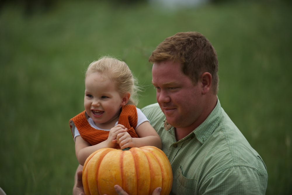 man holding toddler and pumkin