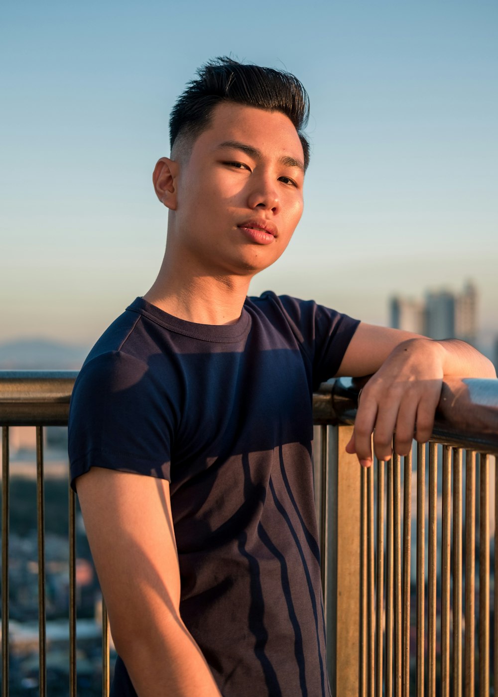 man wearing black t-shirt leaning on metal railings