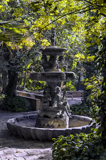 A serene fountain in the château's park with water gently cascading over stone sculptures