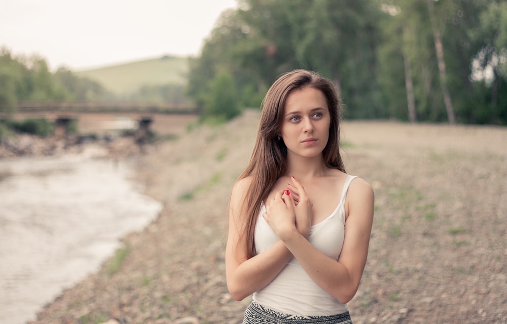 femme portant une camisole blanche près d’un ruisseau d’eau