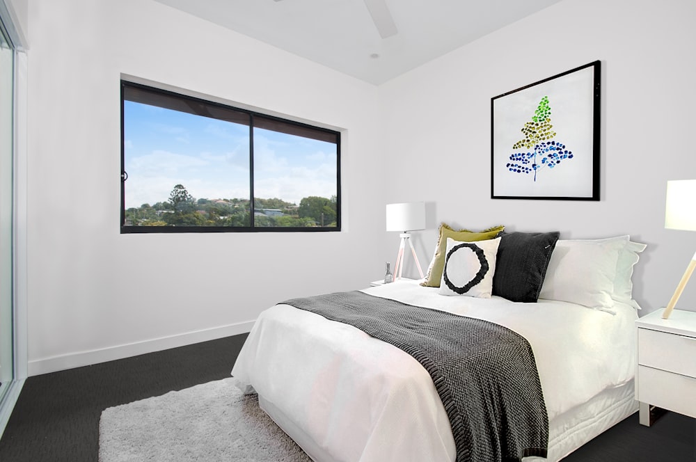 white bedspread on bed near window