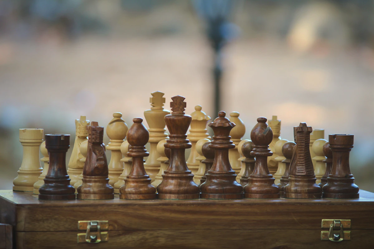 Hand-carved wooden chess pieces on a walnut case in soft golden light