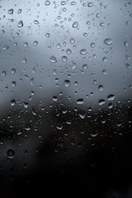 Close-up of raindrops falling softly on a windowpane during a calm evening.