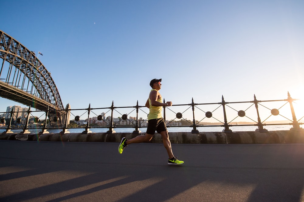 man in yellow tank top jogging along shoreline