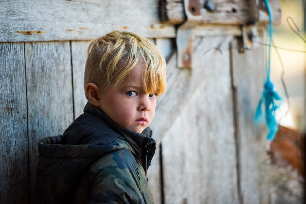 shallow focus photo of boy in green and black woodland camouflage hoodie