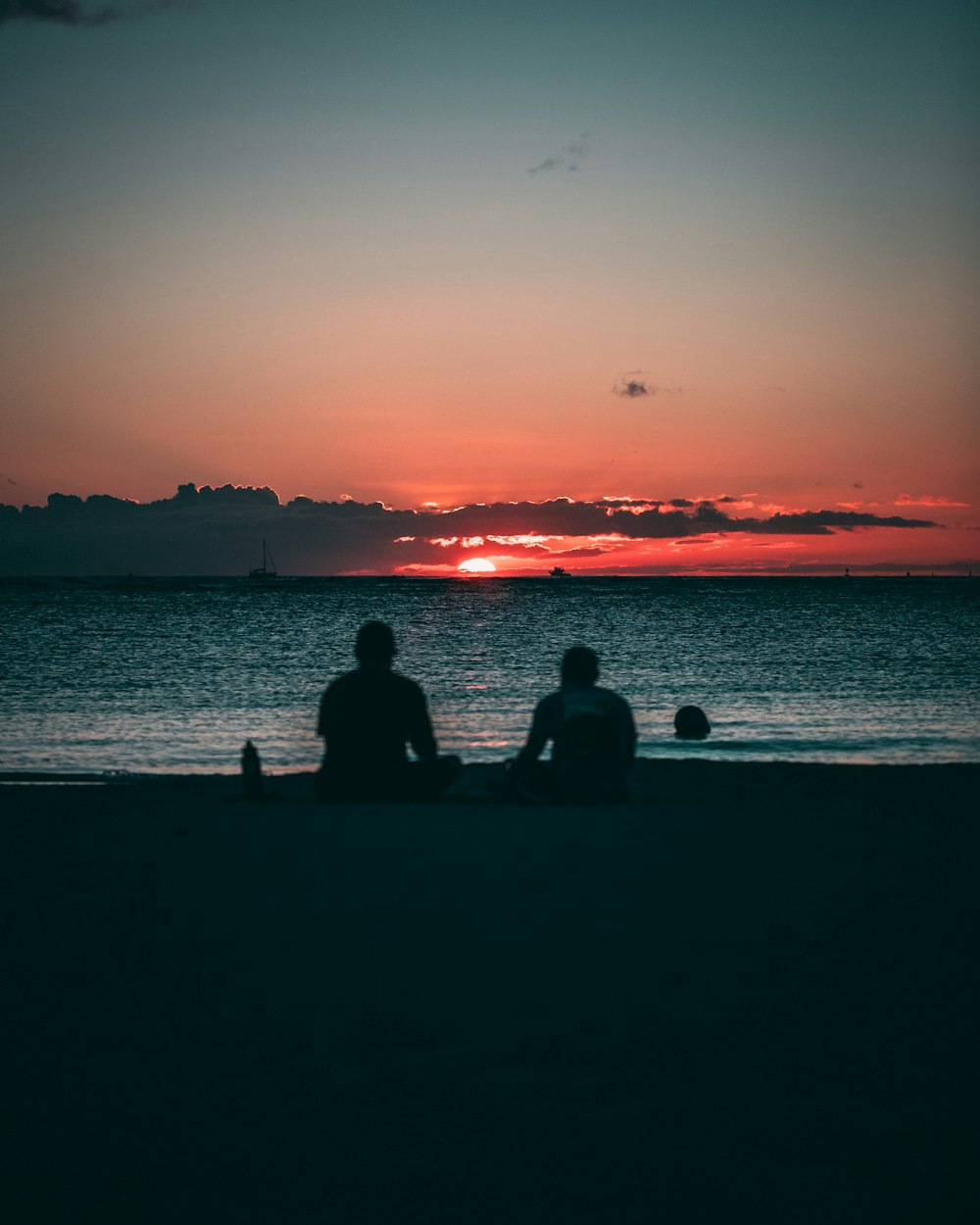 silhouette of two person sitting on sand