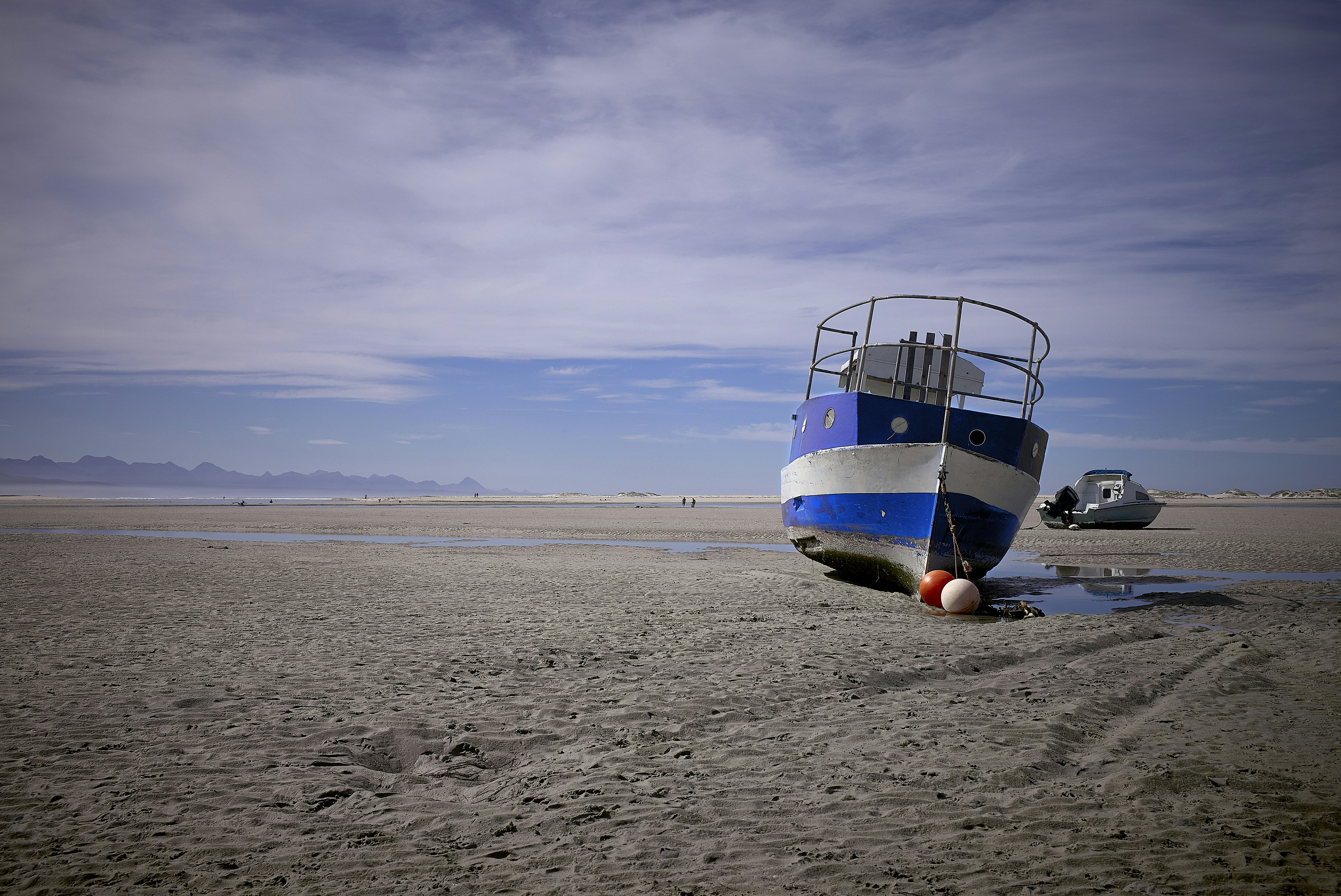 white and blue boat on brown sand during daytime