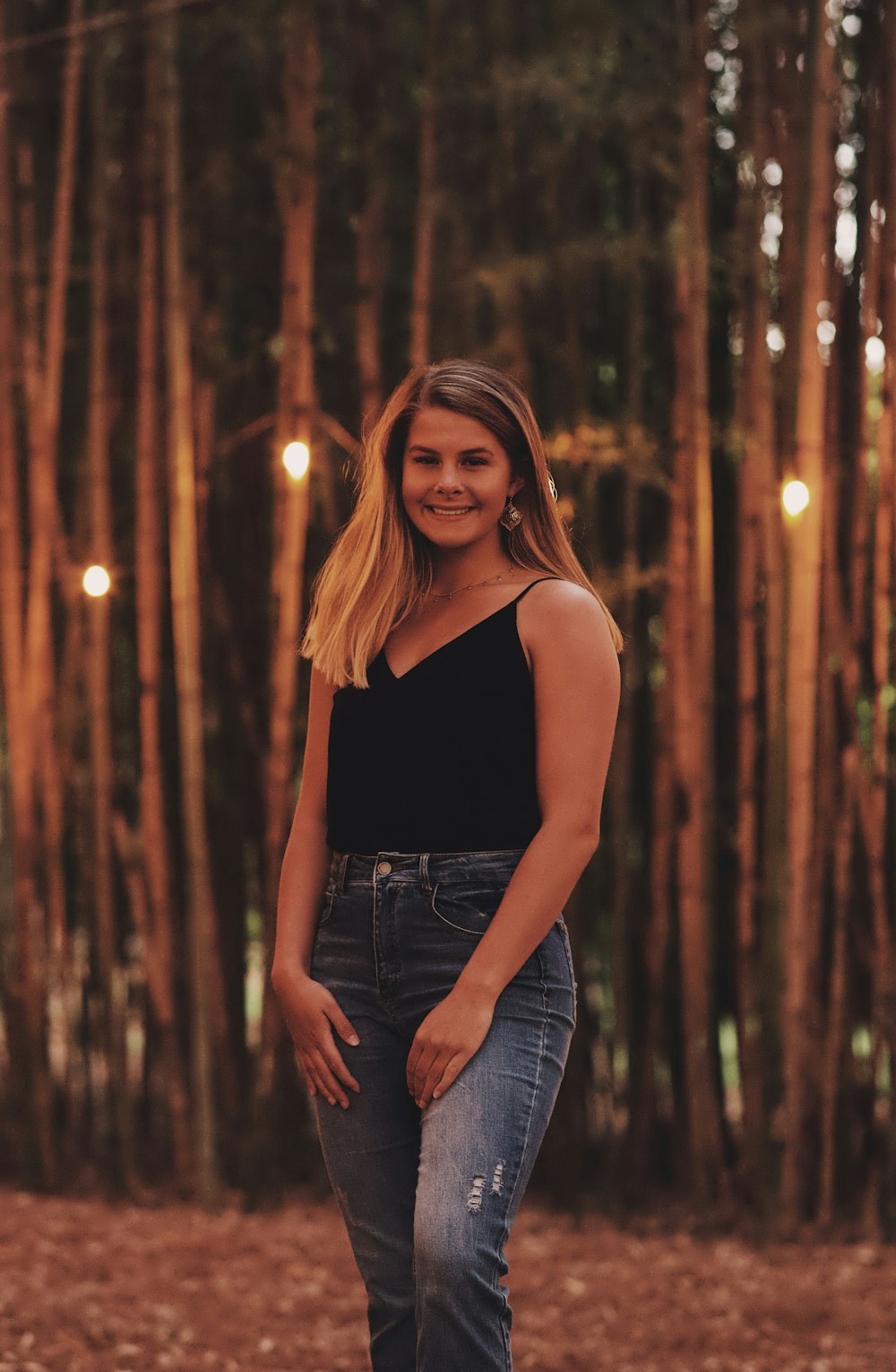 woman smiling while standing on ground near trees