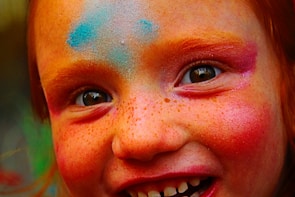 Vibrant face painting with intricate floral designs on a smiling child.