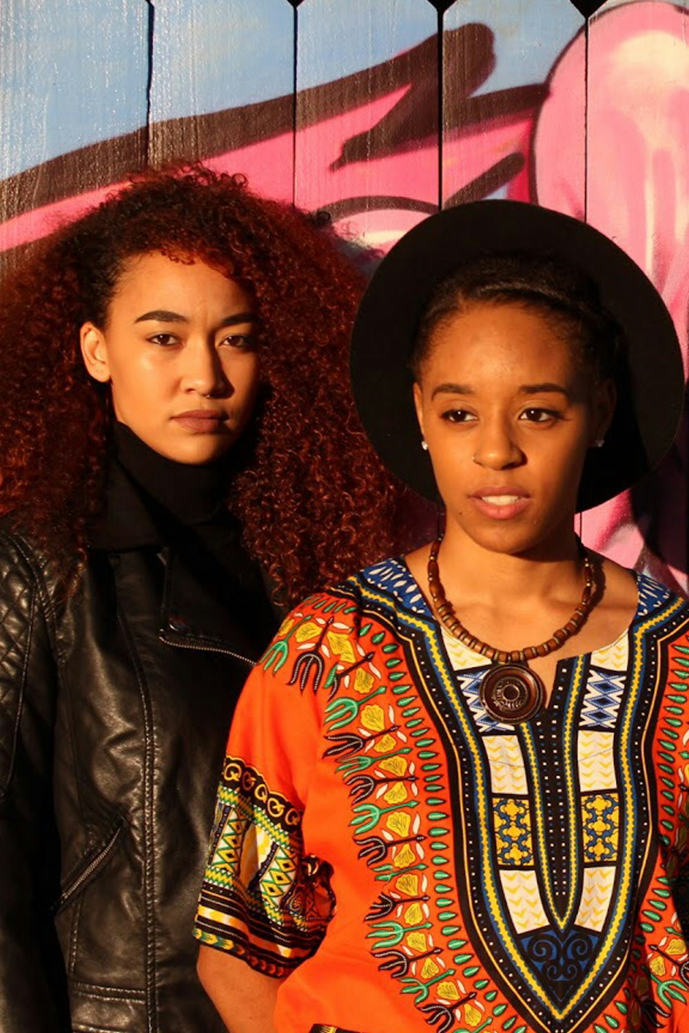 woman wearing dashiki shirt standing beside woman in jacket