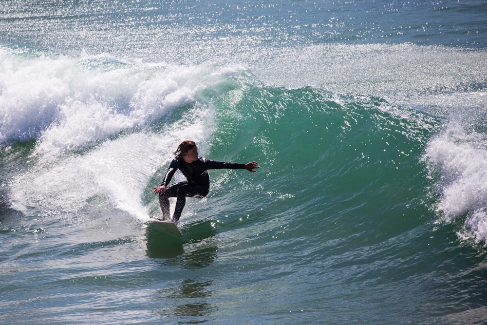 person in black surfing the waves