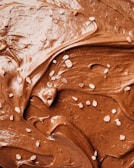 Rich, creamy chocolate spread with a smooth texture is swirled across the surface. Sprinkled lightly are small crystals of salt, contrasting with the glossy sheen of the chocolate.