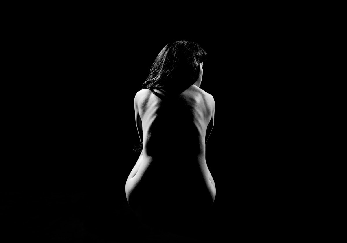 Black and white image of a woman's back with the spine in shadows and her sides beautifully lit.