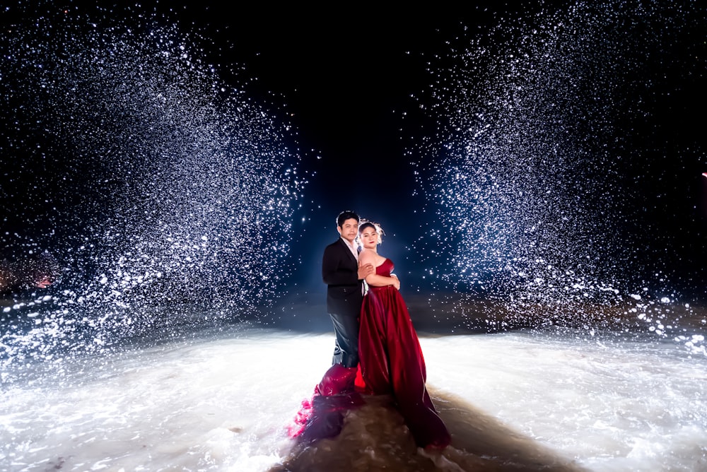 woman and man standing near body of water