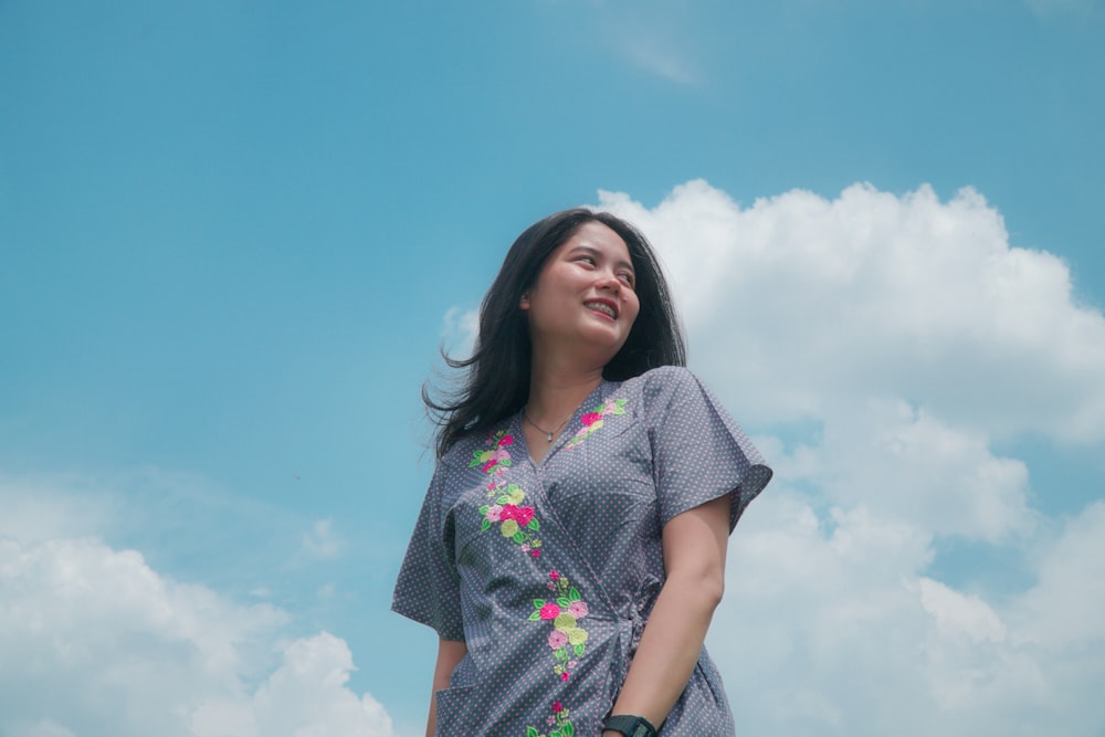 woman wearing gray floral top under white and blue clouds