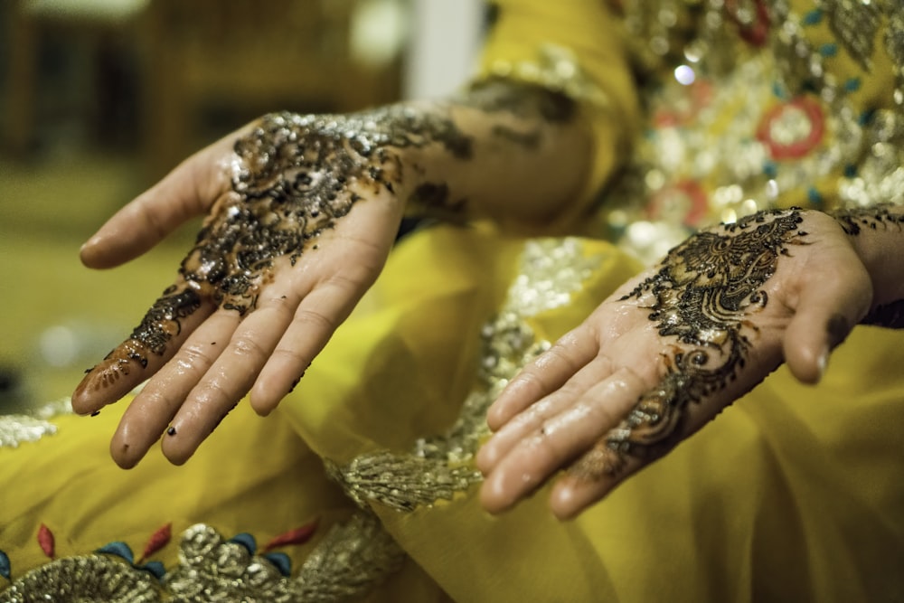 Mani della persona con i tatuaggi di Mehndi