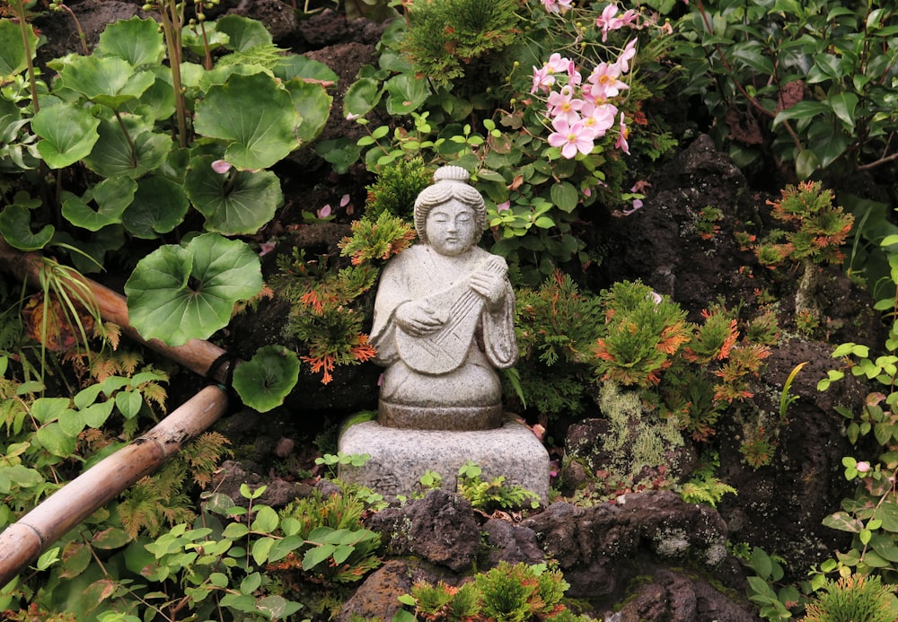 woman playing guitar mini statue near flower garden