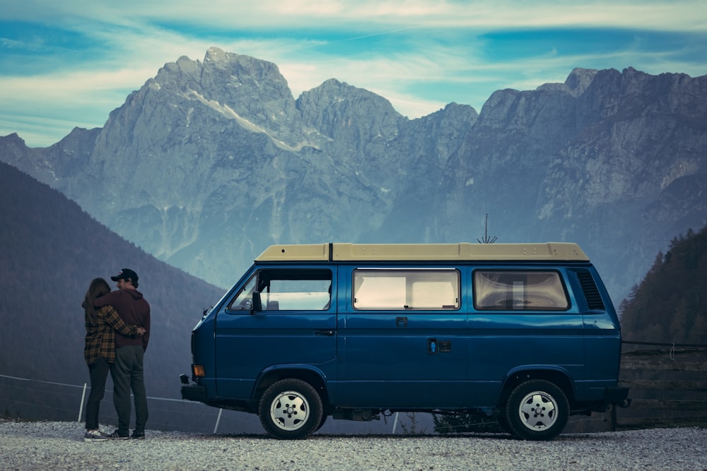 man and woman standing beside blue van