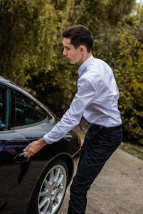 A friendly driver opening the door of a sleek black car at Bergamo airport terminal.