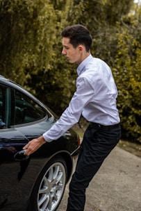 A stylish chauffeur opening a car door for a passenger.