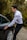 A driver opening a car door for a passenger near a countryside path.