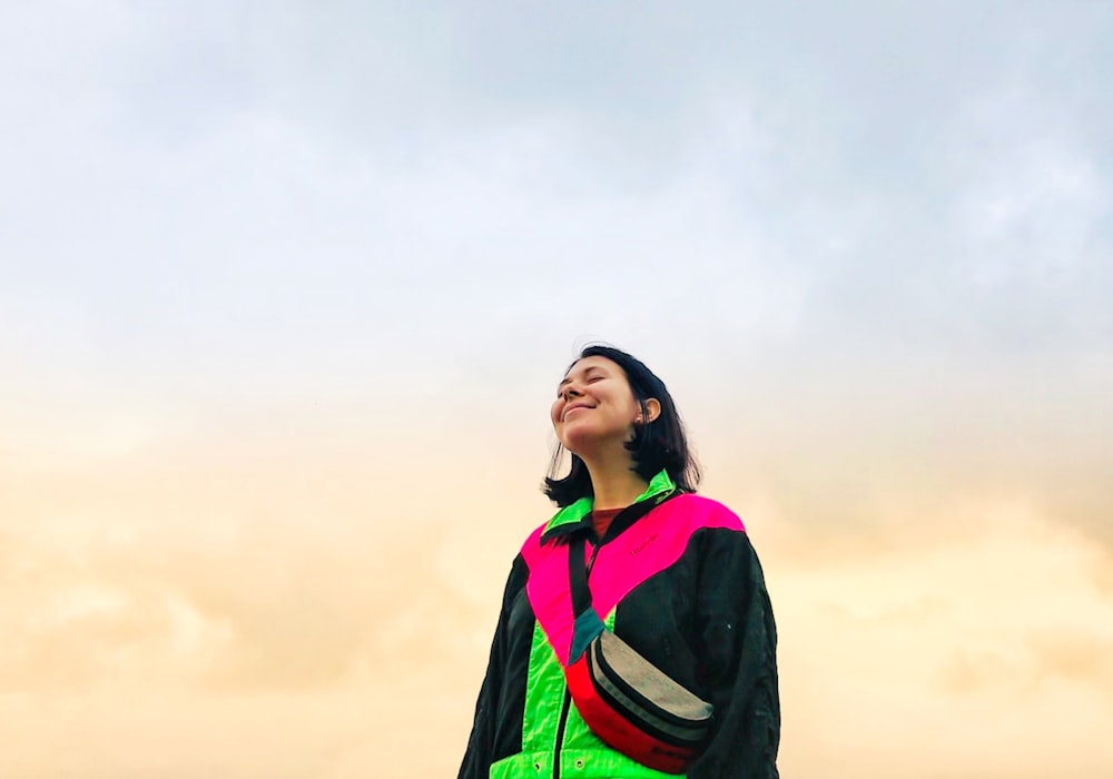 woman in multicolored jacket under gray sky
