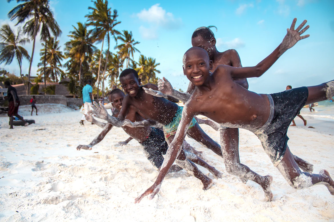 Local children playing and diving on Mombasa beach sand