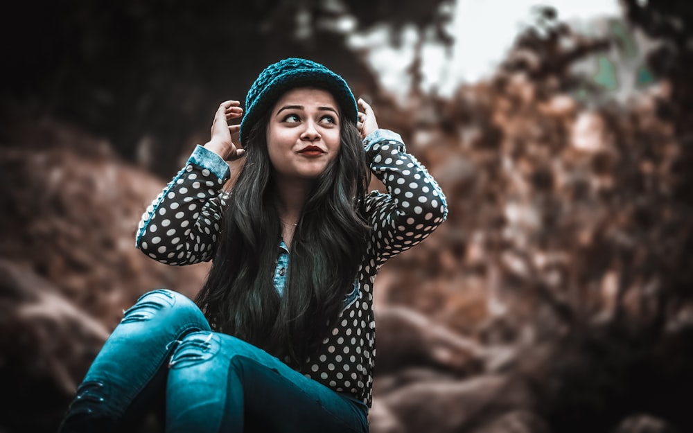 selective focus photography of woman wearing hat sitting near plant