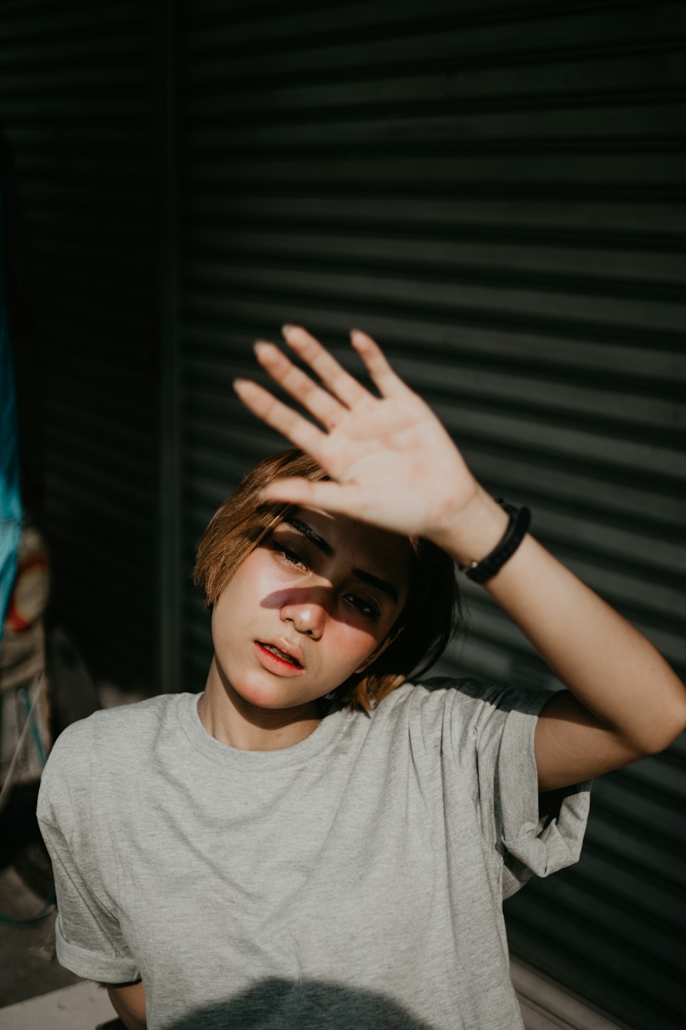 person in grey crew-neck t-shirt covering face with hands