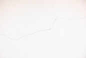 A white wall with visible thin cracks running across its surface.